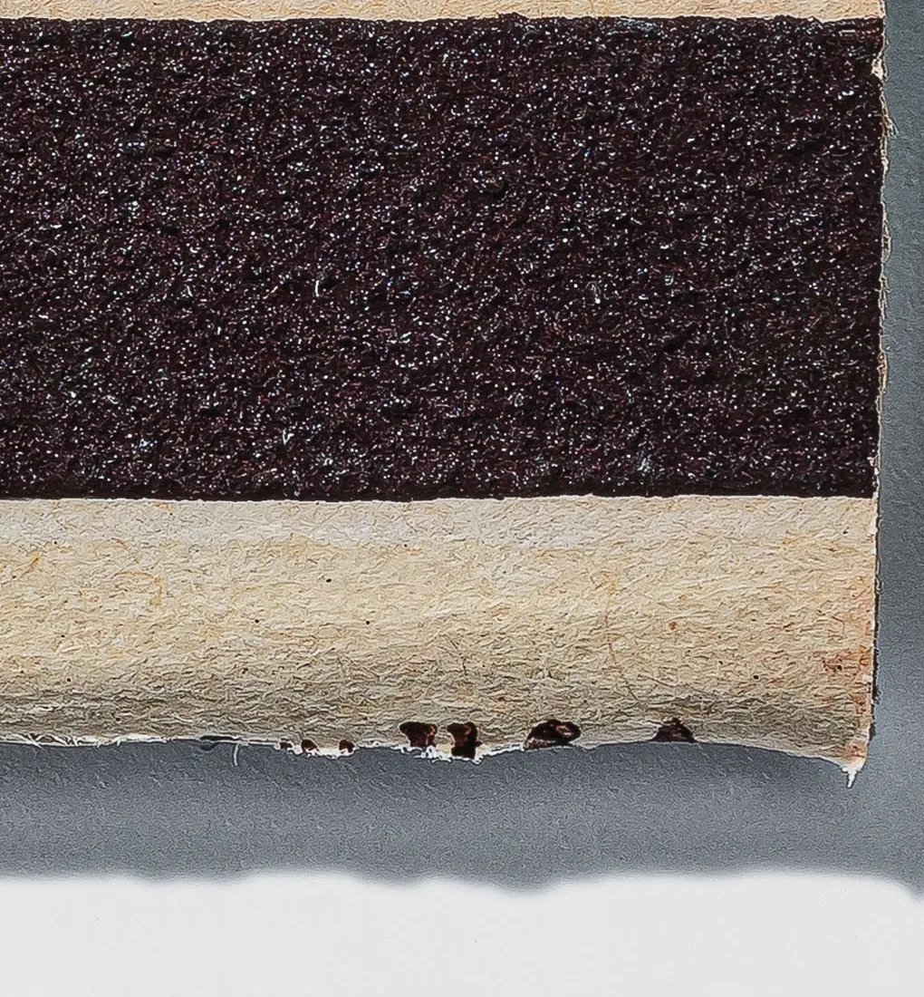 Macro detail of a matchbook's striker strip and its worn, torn edge