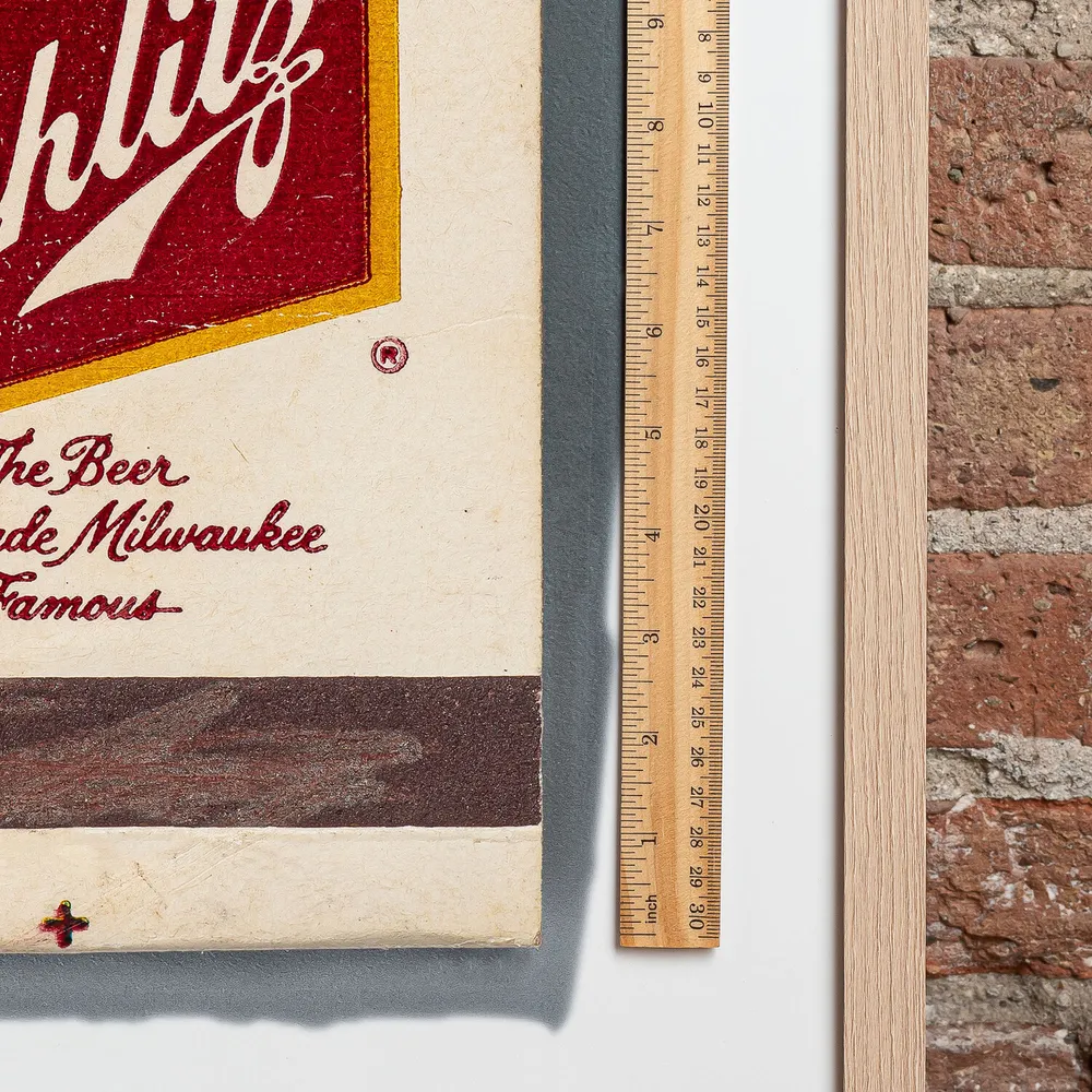 Schlitz matchbook next to a framed print, for scale